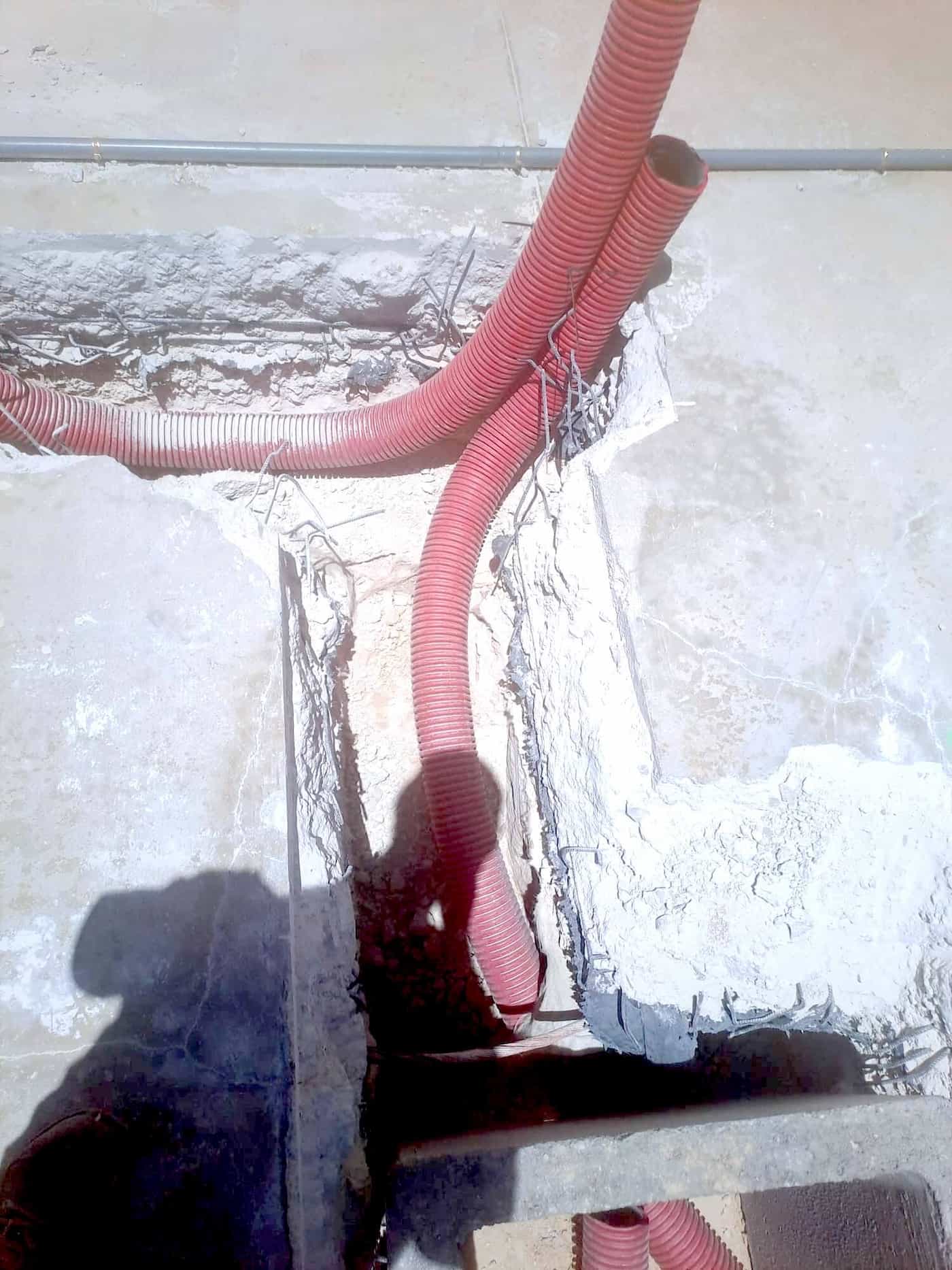 Instalación de tuberías subterráneas en zanja junto a muro de hormigón