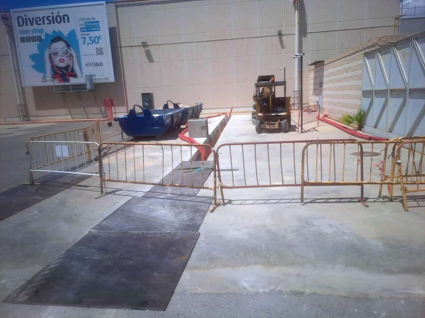 Obra de instalación subterránea con maquinaria en zona comercial